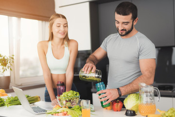 A man and a woman in the kitchen in the morning. The man cooked a green vegetable cocktail and poured it to the woman.