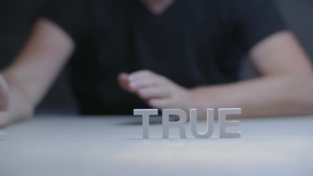 Male hand transforms word not true to true on gray background