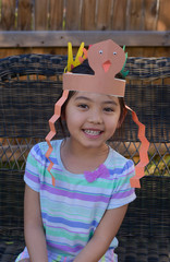 Little girl wearing Thanksgiving turkey artwork from school on her head, filtered tones