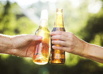 Closeup of hands clinging beer bottle together