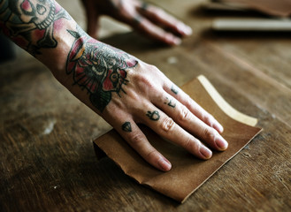 Hands with tattoo using sandpaper on a wood