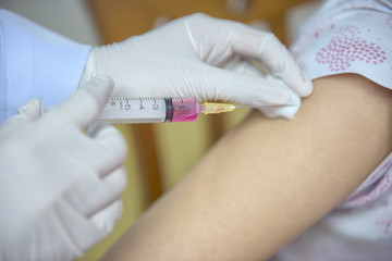 Soft focus nurses are vaccinations to patients using the syringe.Doctor vaccinating women in...