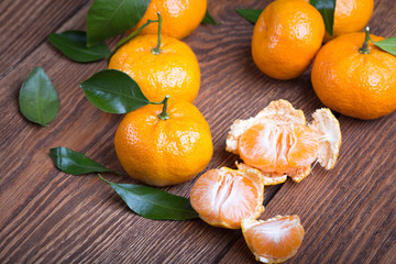 Fresh mandarin orange with green leaves and slices on wooden background