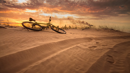 vélo dans le désert / coucher de soleil jaune chaud fin été