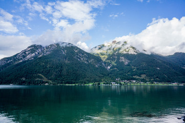 Beautiful landscape Achensee lake, alpine mountains, blue sky and clouds, reflections in water. Tirol, Austria.