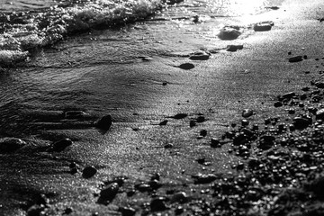A close view of water on a lake shore, with details of sands and little stones