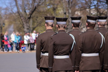 Łotwa, Ryga, oficjalna ceremonia z udziałem łotewskiej armii, święto narodowe Łotwy, grupa żołnierzy, tyłem, na drugim planie niewyraźna grupa ludzi uczestnicząca w święcie, park - obrazy, fototapety, plakaty
