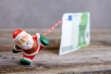 Naklejka premium little Santa Claus pulling big banknote