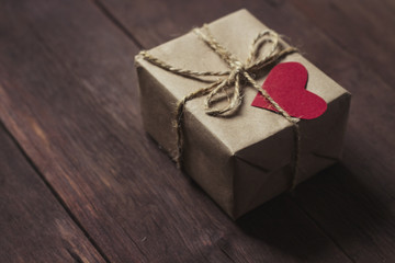 Gift box with red heart on a wooden background
