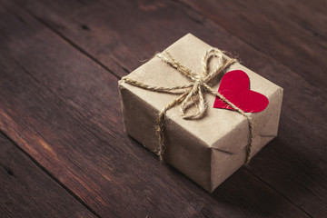 Small gift box with heart on wooden background