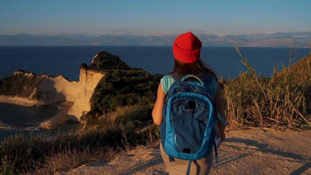Woman with a backpack and map goes to the Cape Drastis at Corfu island in Greece