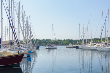 Fototapeta na wymiar Sailboat leaving harbor, Yachts and boats parked in harbor, sunrise, morning