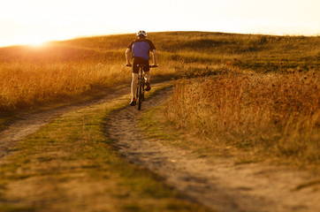 Male cyclist driving by rural dirt road outdoors