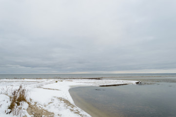 Fototapeta na wymiar frozen rocky sea beach with snow and ice