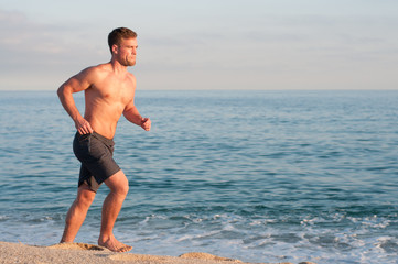 Fototapeta na wymiar Muscular man barefoot running on beach