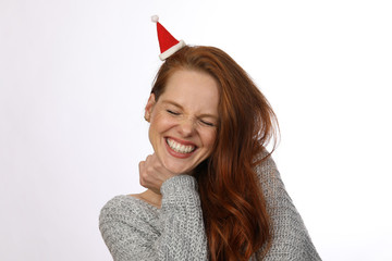 Hübsche rothaarige Frau mit kleiner Weihnachtsmütze lacht