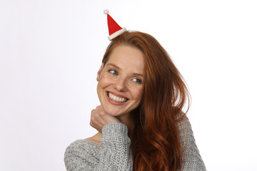 Hübsche rothaarige Frau mit Weihnachtsmütze lacht