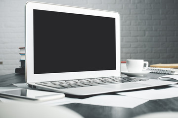 Light office desktop with blank laptop screen