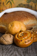 Different types of fresh bread and wheat spikes on old wooden table. Shallow depth of field. Selective focus