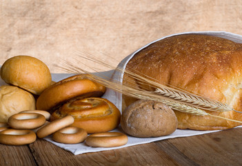 Different types of fresh bread and wheat spikes on old wooden table. Shallow depth of field. Selective focus