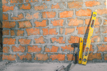 Mason bricklaying background with level, hammer and clay brick blocks