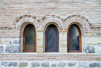 Fototapeta na wymiar Three small arch windows on a brick wall