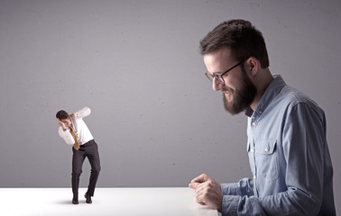 Young businessman fighting with miniature businessman