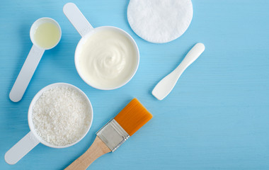 Sour cream (greek yogurt), shredded coconut and olive oil in a small plastic scoops - ingredients for preparing diy masks, scrubs and moisturizers. Homemade cosmetics. Top view, copy space.