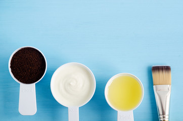 Sour cream (greek yogurt), raw egg, ground coffee and olive oil in a small plastic scoops - ingredients for preparing diy masks, scrubs and moisturizers. Homemade cosmetics. Top view, copy space.