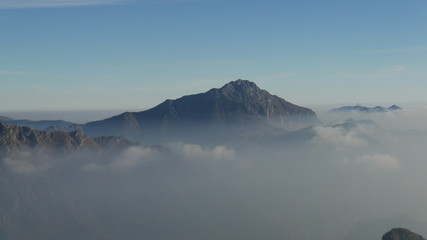 Panorama dalla vetta della montagna sulle Alpi con nebbia e nuvole in pianura