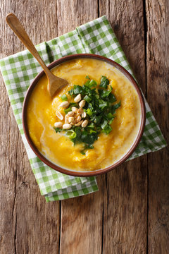 spicy Thai pumpkin soup with peanuts and cilantro close-up in a bowl. Vertical top view
