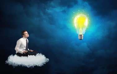 Fototapeta na wymiar Man sitting on cloud looking at a lightbulb