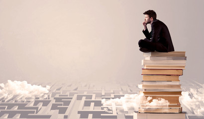 Businessman sitting on books in labirynth