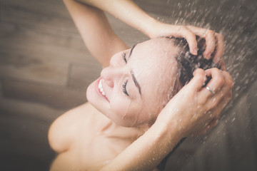 Young beautyful woman under shower in bathroom.