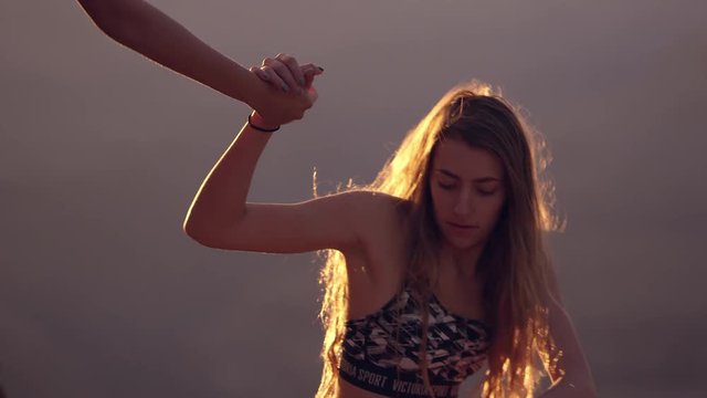 Young woman offers hand to help twin sister stand up as they walk away.