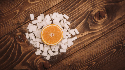 Fresh orange on bunch of sugar cubes and granulated sugar