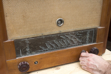 Męska dłoń włącza stare lampowe zabytkowe radio.