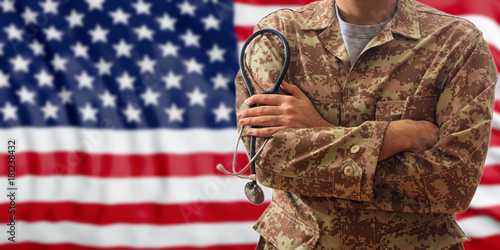 Doctor with stethoscope in an American military uniform, standing on a USA flag background