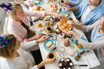 One of females by dinner table taking pancake from plate being offered by her friend
