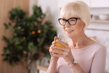 Cheerful elderly woman drinking orange juice