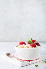 Oat granola with berries and yoghurt on light gray background. Copy space. Healthy breakfast concept.