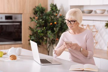 Nice smiling elderly woman using her smartphone