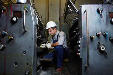 Handyman with industrial handtool repairing factory equipment