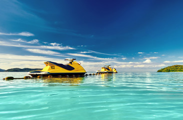 Yellow Jet ski on the sea and blue sky and small islands in background.