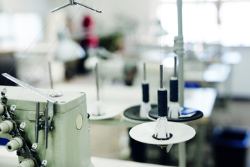 Thread spool ready for usage and part of sewing machine in tailor workshop