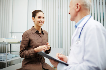 Fototapeta premium Happy young woman visiting doctor and listening to his advice during appointment