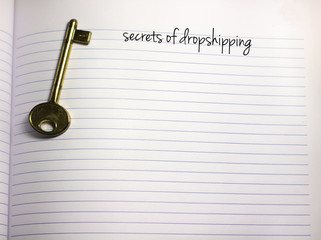 secrets of dropshipping handwriiten text on a blank white empty paper with a key on the side and...