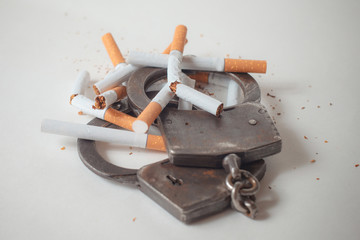 Addition concept with cigarettes and handcuffs on white background