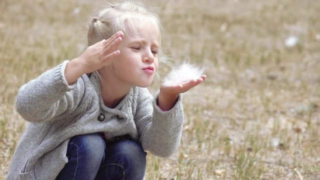 Girl child blowing fluff of bulrush