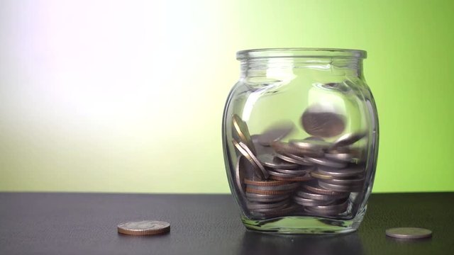 Savings in the jar, coins falling into the jar with green background